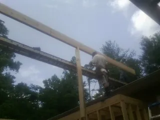 Carpenter setting a ridge beam over a new addition frame — Ice Dam Removal by Roofing Brothers in Wilderville