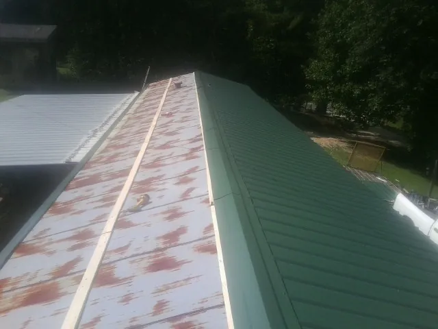 Old rusted panels beside newly installed green metal roofing — Wind Damage Roof Repair by Roofing Brothers in Wilderville