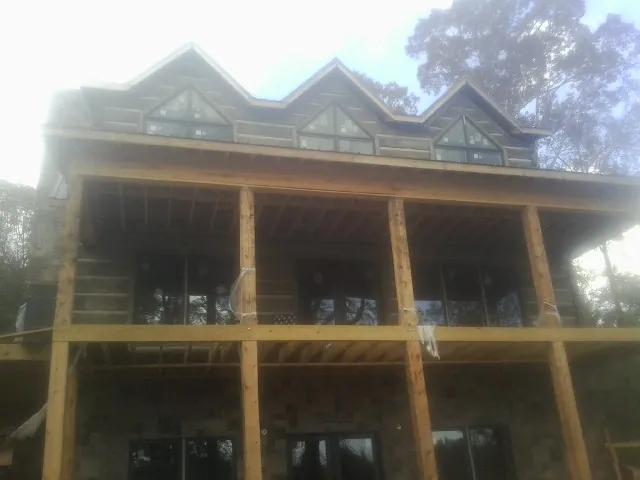 Dormers and porch framing on a large log home under construction — Roof Coating work by our crew in Wilderville