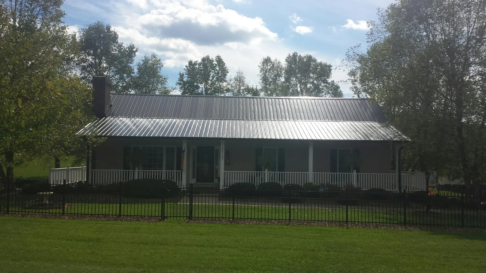 Gray metal roof on a brick ranch with a full width front porch — Gutter Guard Installation work by our crew in Wilderville