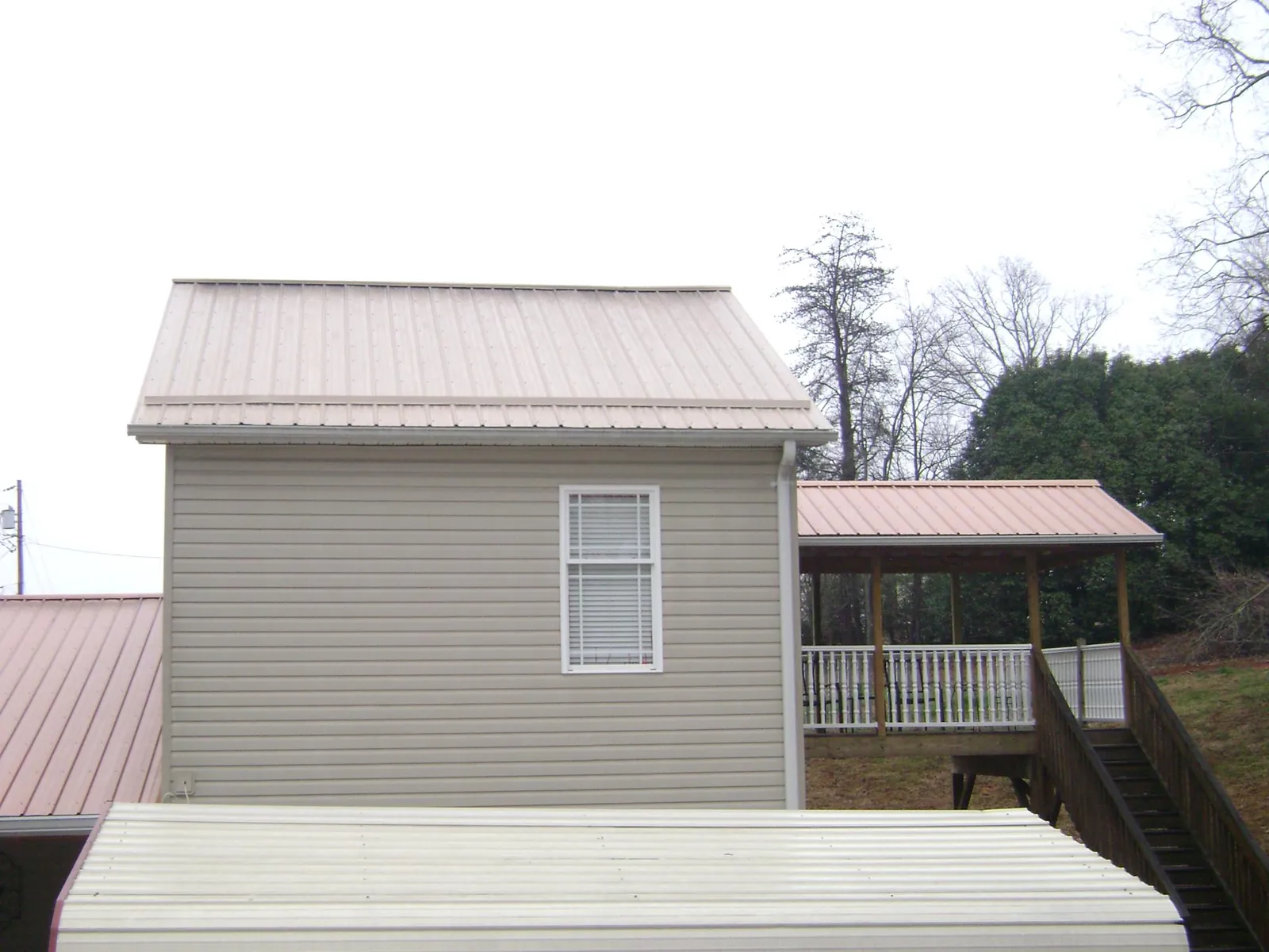 Tan metal roofs on a two story addition and attached porch, from a Roof Replacement job in Wilderville